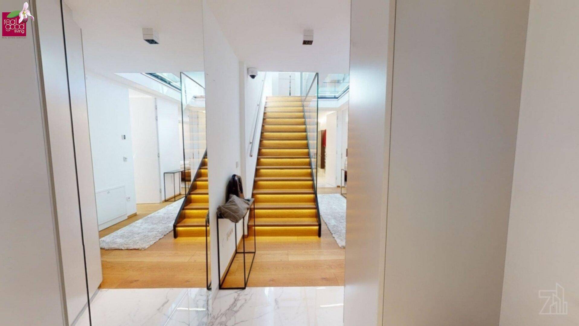 Geräumiger Eingangsbereich mit moderner Treppe und elegantem Marmorboden.
