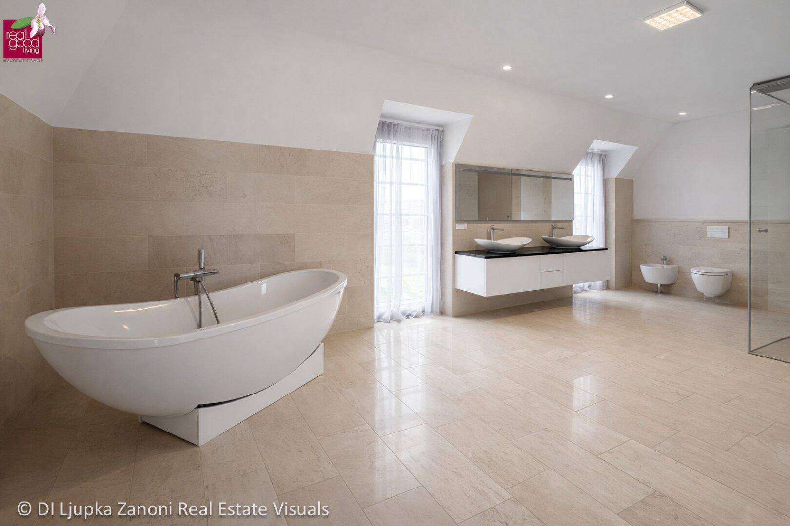 Geräumiges Badezimmer mit freistehender Badewanne, Doppelwaschbecken und modernen Armaturen.
