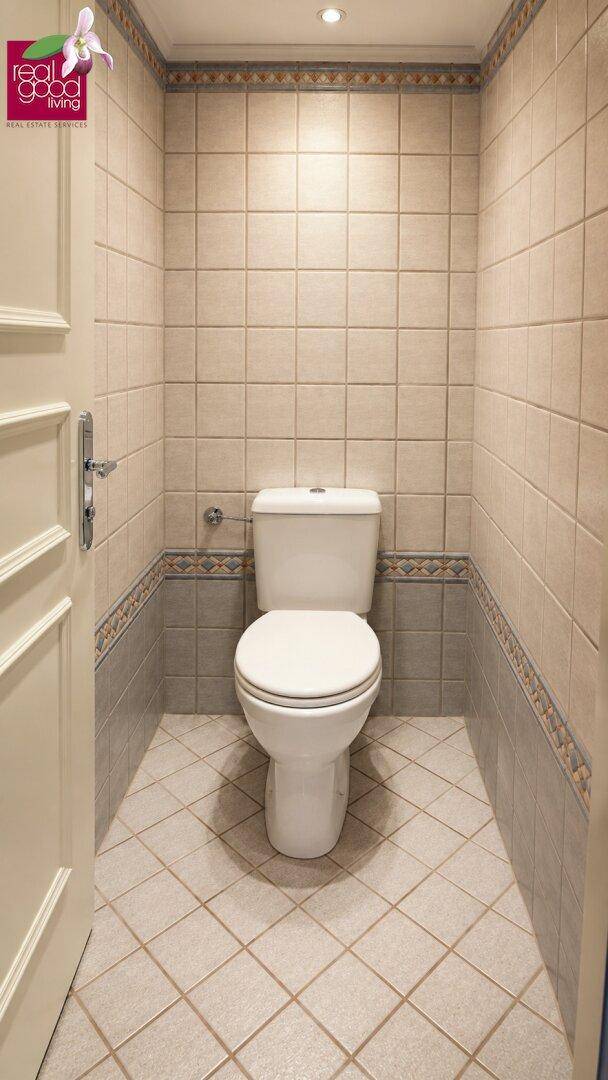 Separate Toilette mit Fliesen an Wänden und Boden in neutralen Farbtönen.