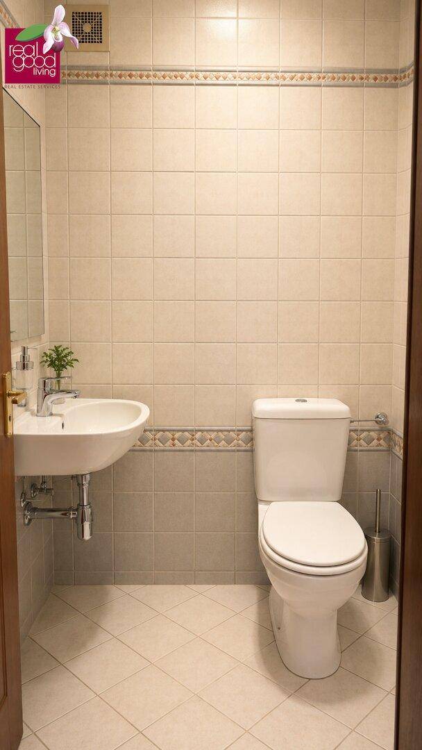 Kleines Gäste-WC mit Waschbecken, Toilette und hellen Fliesen.