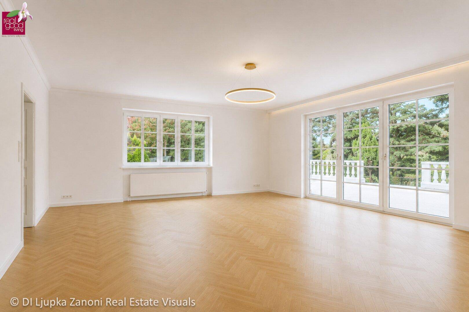 Geräumiges, helles Wohnzimmer mit Fischgrätparkett und großen Fenstertüren zur Terrasse.