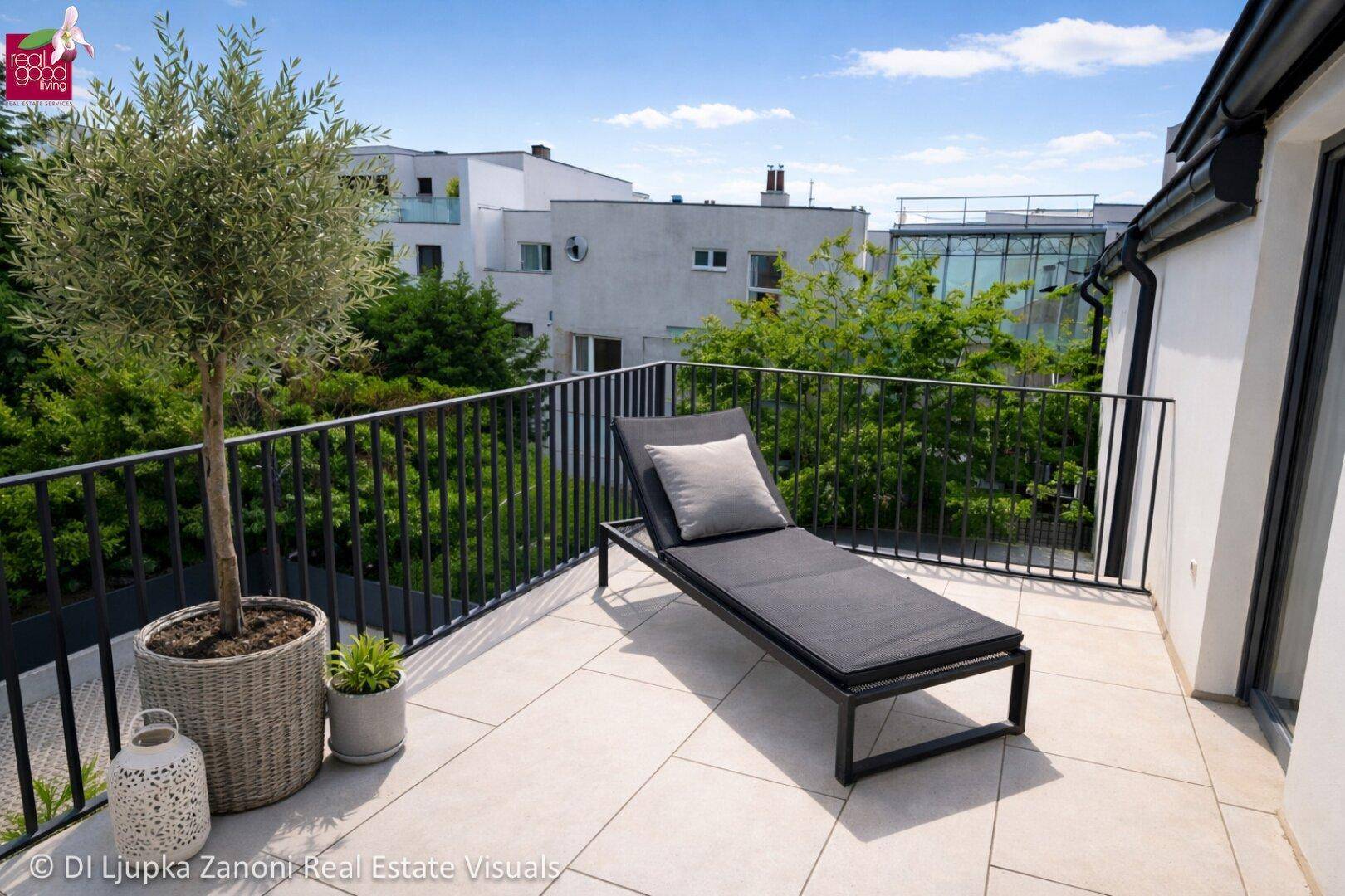 Sonnige Dachterrasse mit Liegestuhl und Blick auf moderne Gebäude und grüne Umgebung.