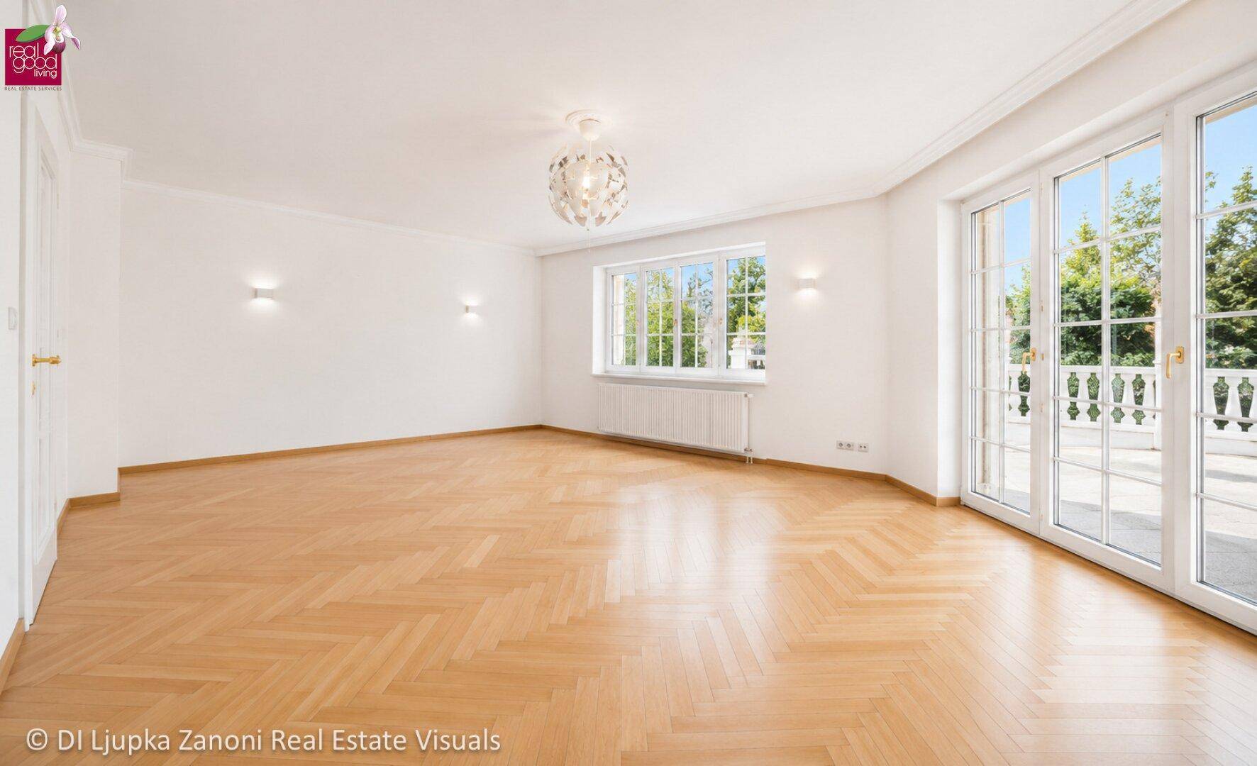 Geräumiges, helles Wohnzimmer mit Fischgrätparkett und großen Fenstertüren zur Terrasse.