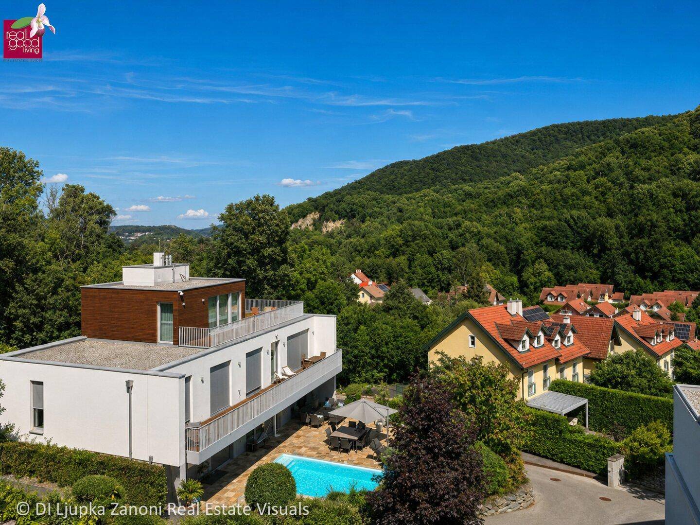 Luftaufnahme einer modernen Wohnanlage mit Pool, Terrassen und weitem Blick auf die Landschaft.