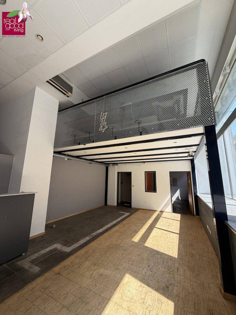 Großer, heller Gewerberaum mit hohen Decken, einer Galerie und gemischtem Bodenbelag.