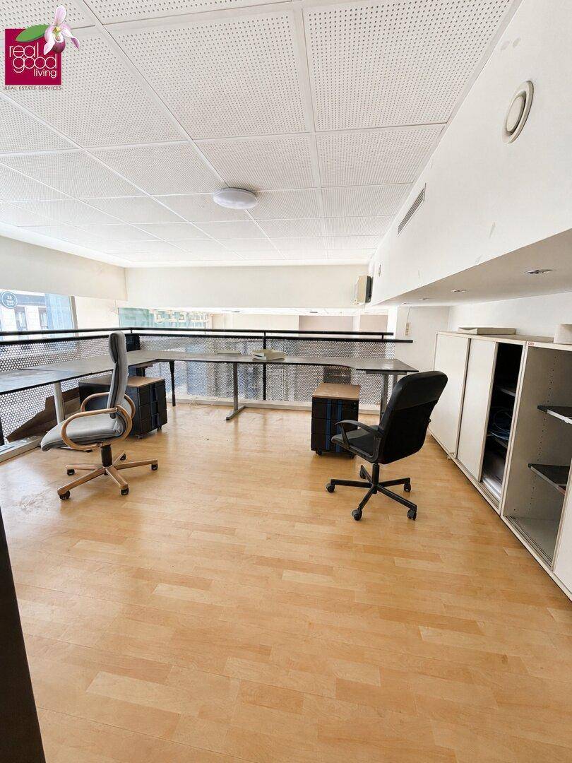 Heller Bürobereich auf einer Galerie mit Holzfußboden und Blick auf den unteren Bereich.