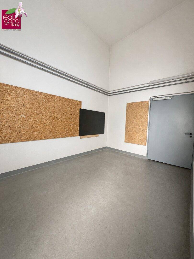 Einfacher Lagerraum mit hellem Boden, weißen Wänden und Holzfaserplatten an der Wand.