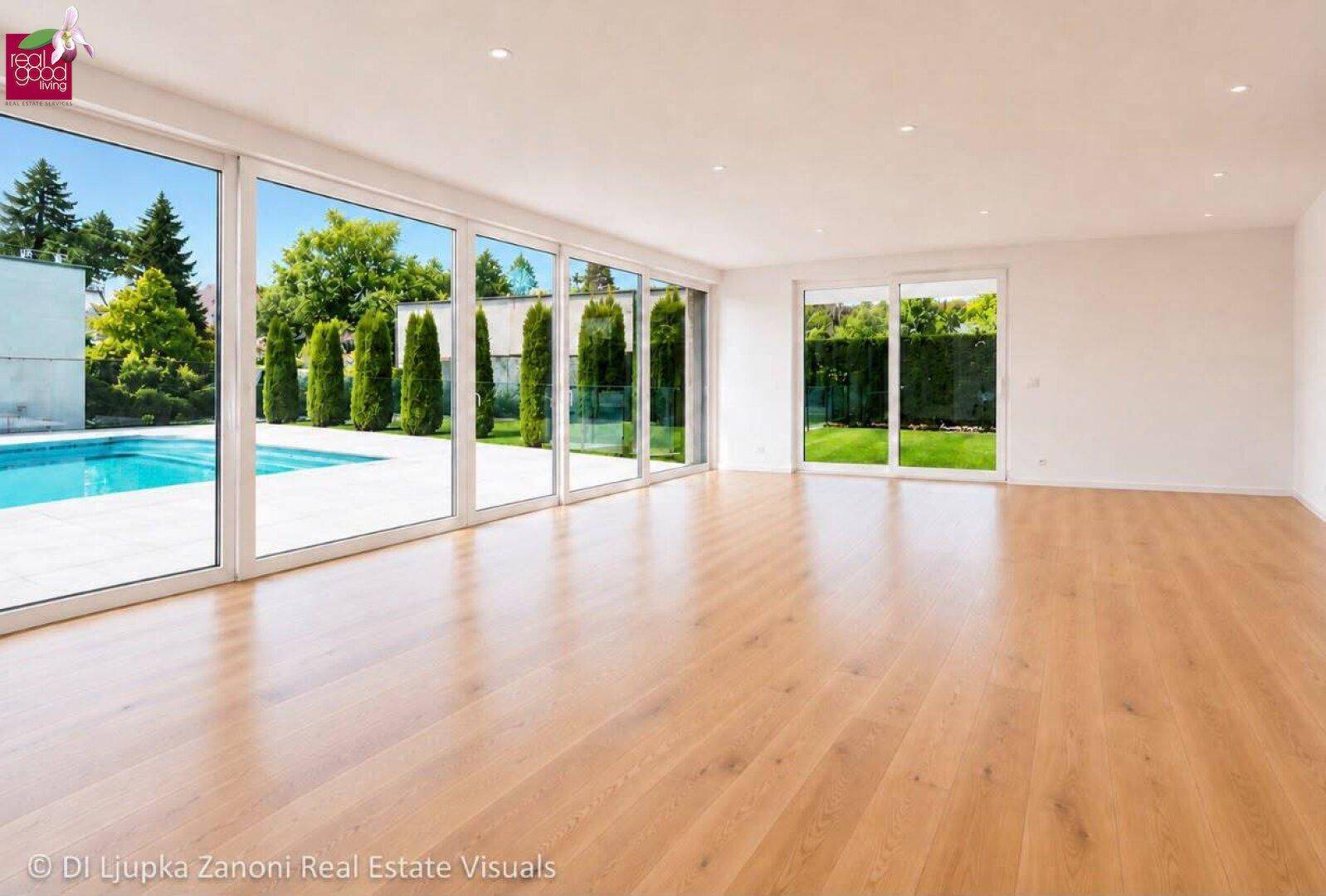 Heller, leerer Wohnbereich mit großen Fensterfronten und Blick auf den Pool und Garten.