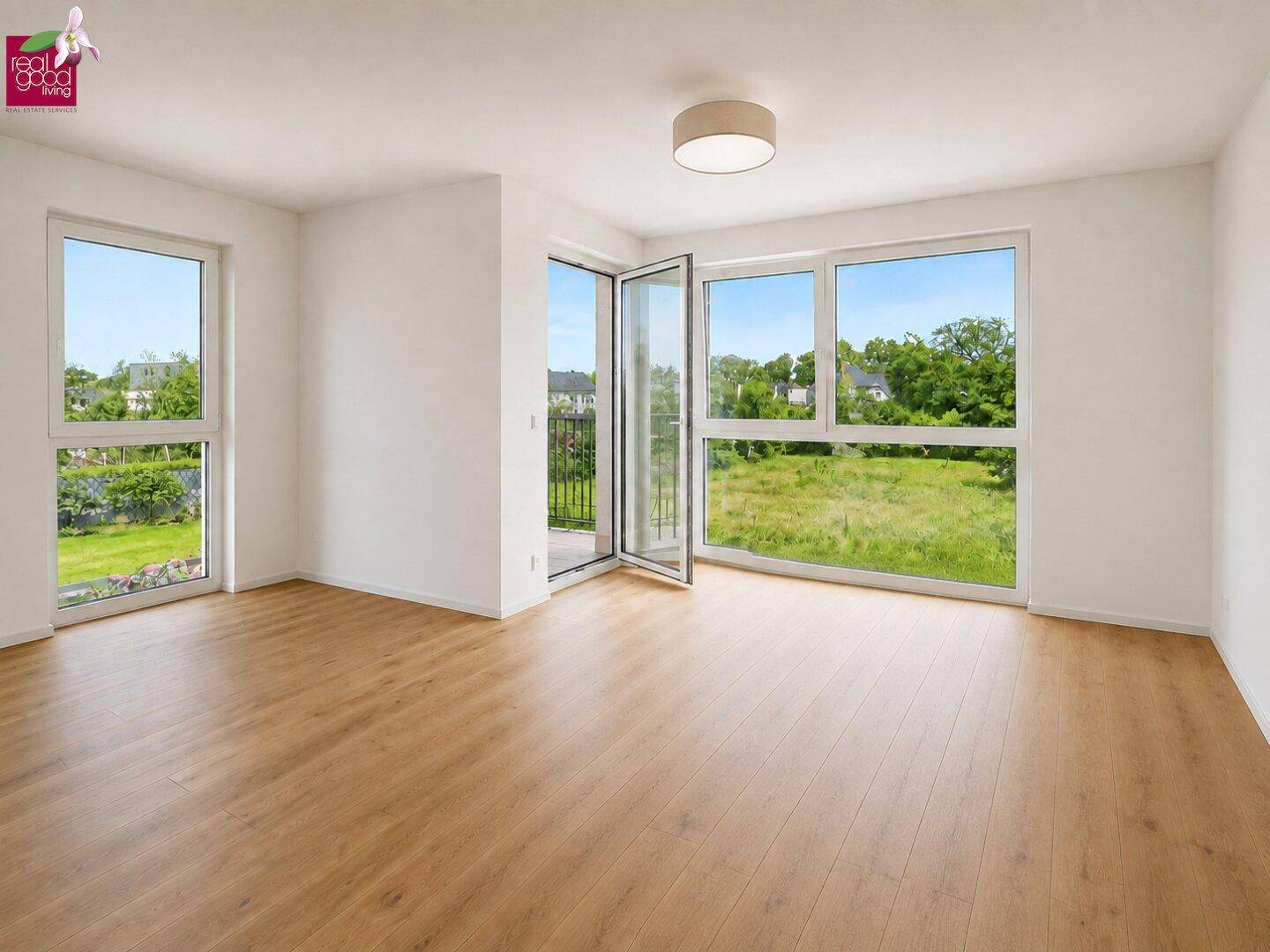 Geräumiges, leeres Schlafzimmer mit Holzboden, Balkonzugang und weitem Blick ins Grüne.