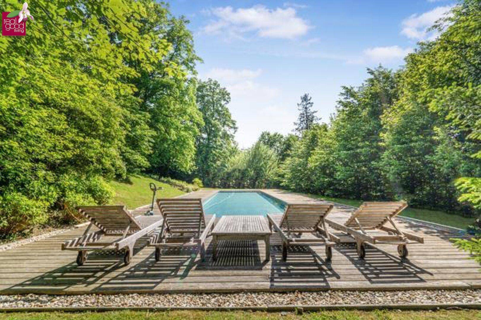 Entspannungsbereich am Pool mit Holzliegen und Blick ins Grüne.
