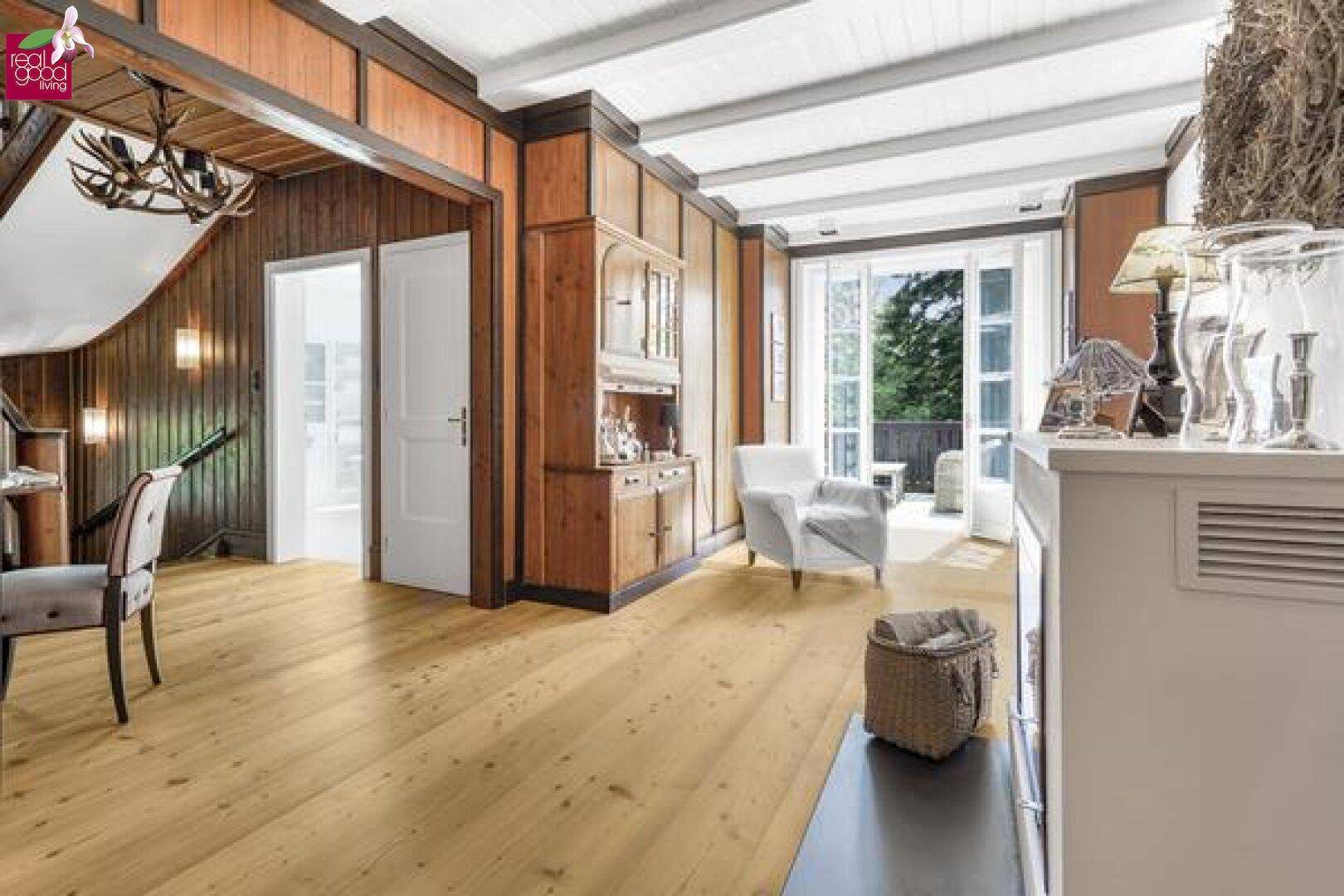 Heller Wohnbereich mit Holzboden, Holzwänden und Zugang zu einem Balkon.