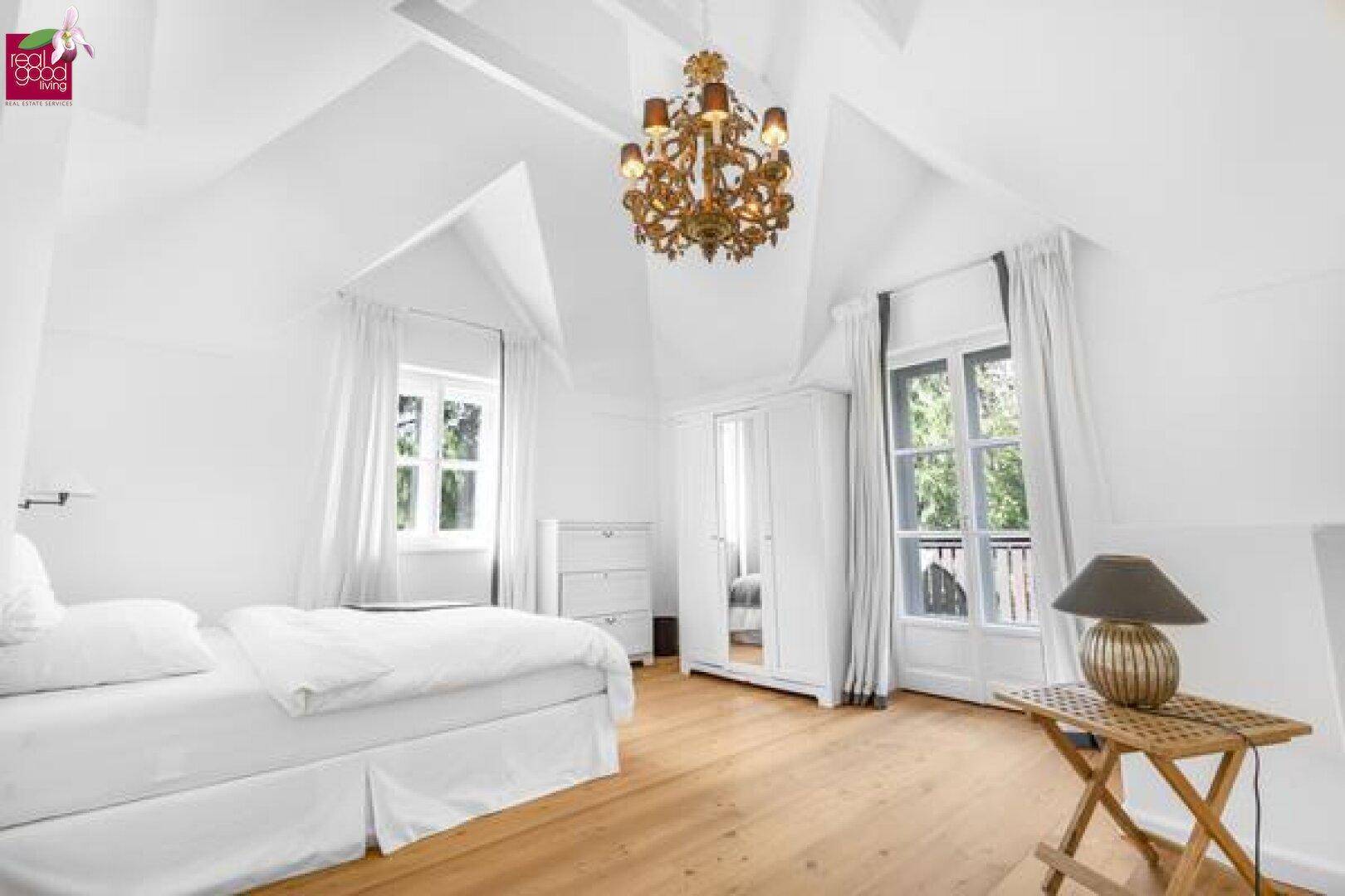 Helles Schlafzimmer im Dachgeschoss mit hohen Decken und Holzboden.