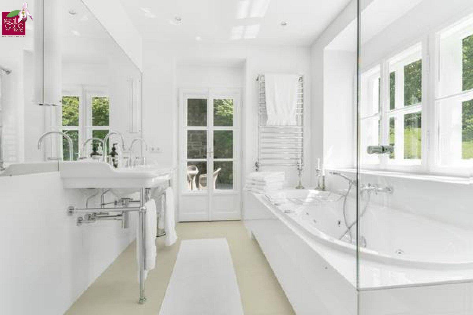 Elegantes, helles Badezimmer mit Doppelwaschbecken, Badewanne und Fenster.