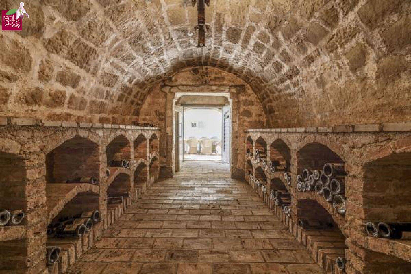 Historischer Weinkeller mit Gewölbedecke, Steinmauern und Weinregalen.