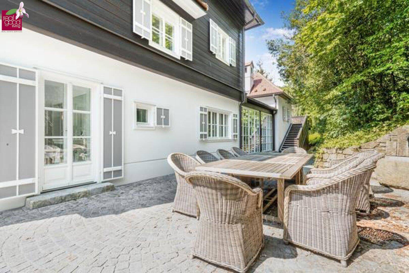 Sonniger Terrassenbereich mit Esstisch und Blick auf das historische Gebäude.