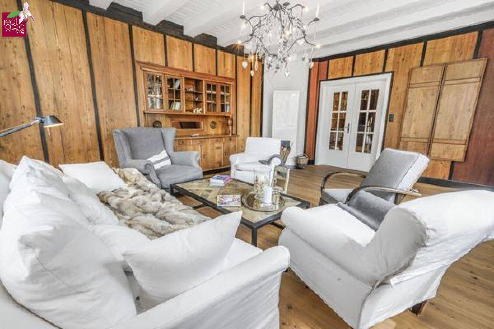 Geräumiges Wohnzimmer mit Holzwänden, Holzboden und eleganten Möbeln.