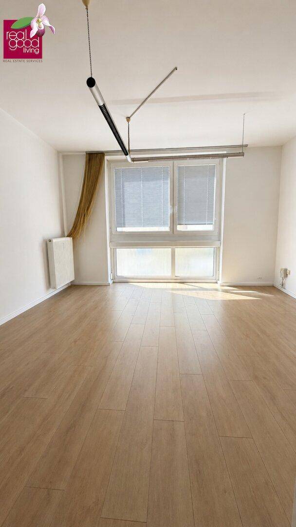 Heller Wohnraum mit Holzboden, großen Fenstern und viel Tageslicht.
