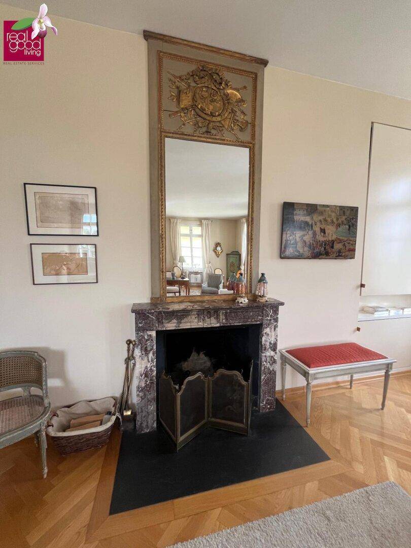Wohnzimmer mit elegantem Marmorkamin, großem Spiegel und Fischgrätparkett.