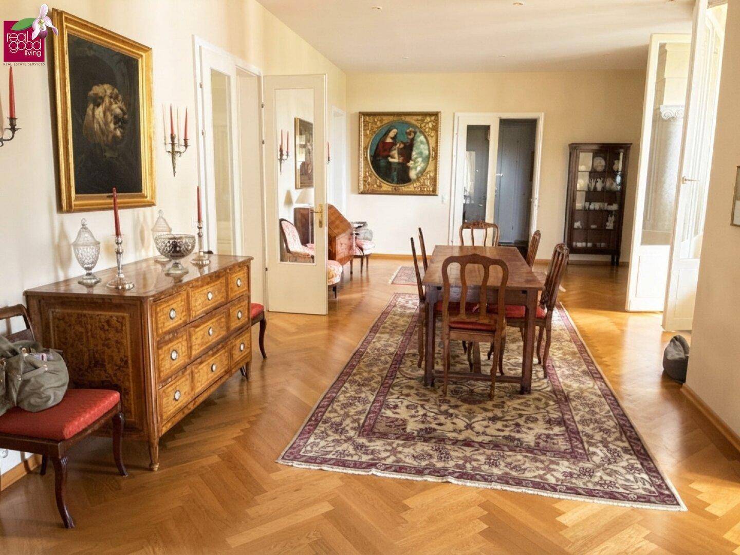 Eleganter Essbereich mit Fischgrätparkett, antiken Möbeln und Kunstwerken an den Wänden.