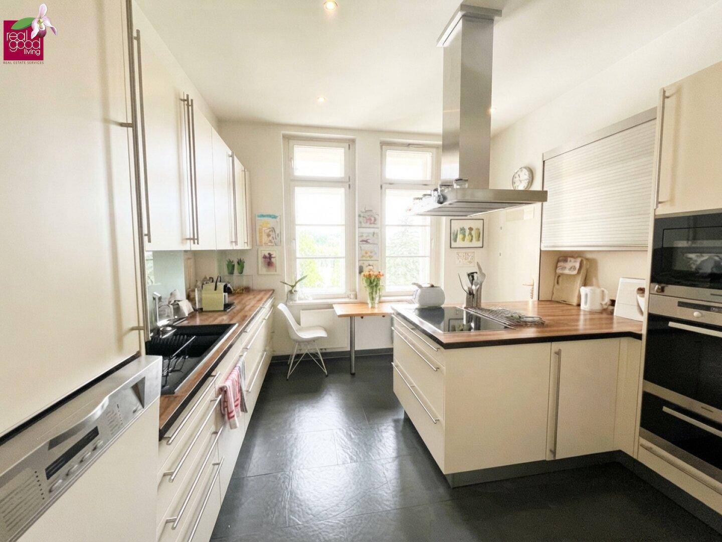 Helle, moderne Küche mit Kochinsel, Einbaugeräten und Fensterblick.