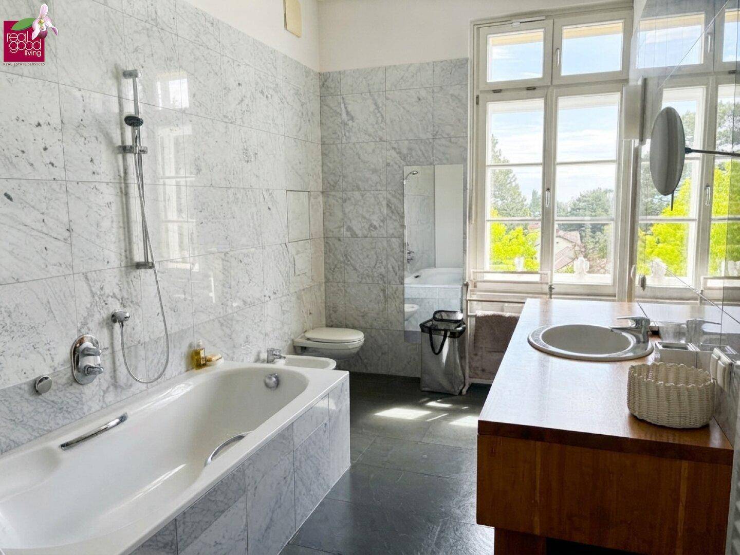 Geräumiges Badezimmer mit Badewanne, Bidet, Einzelwaschbecken und großem Fenster.
