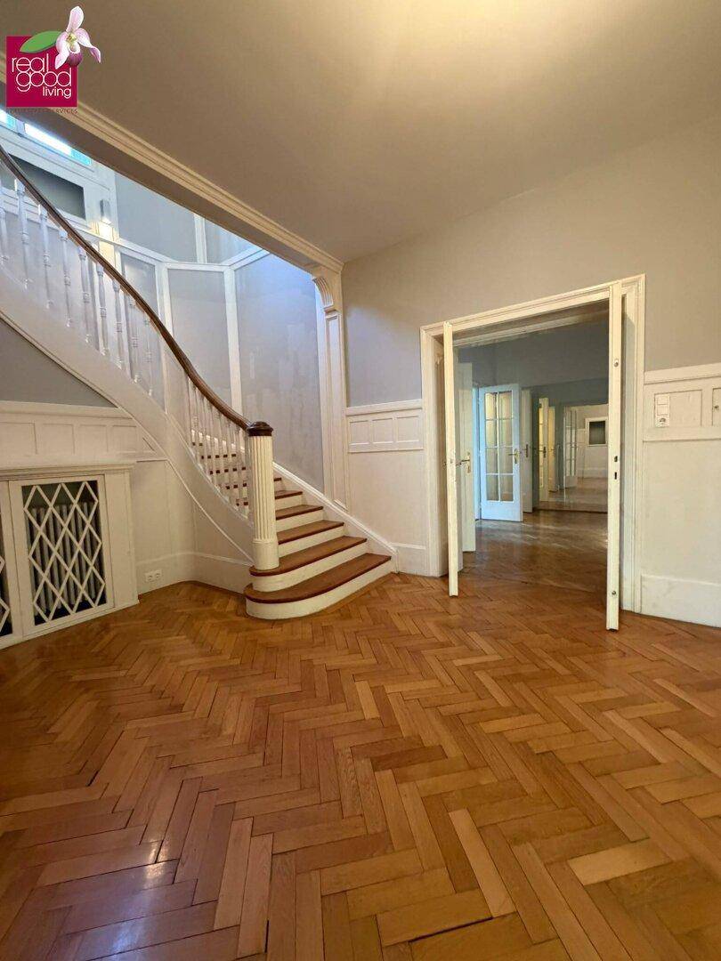 Geräumiger Eingangsbereich mit Fischgrätparkett und einer beeindruckenden Holztreppe.