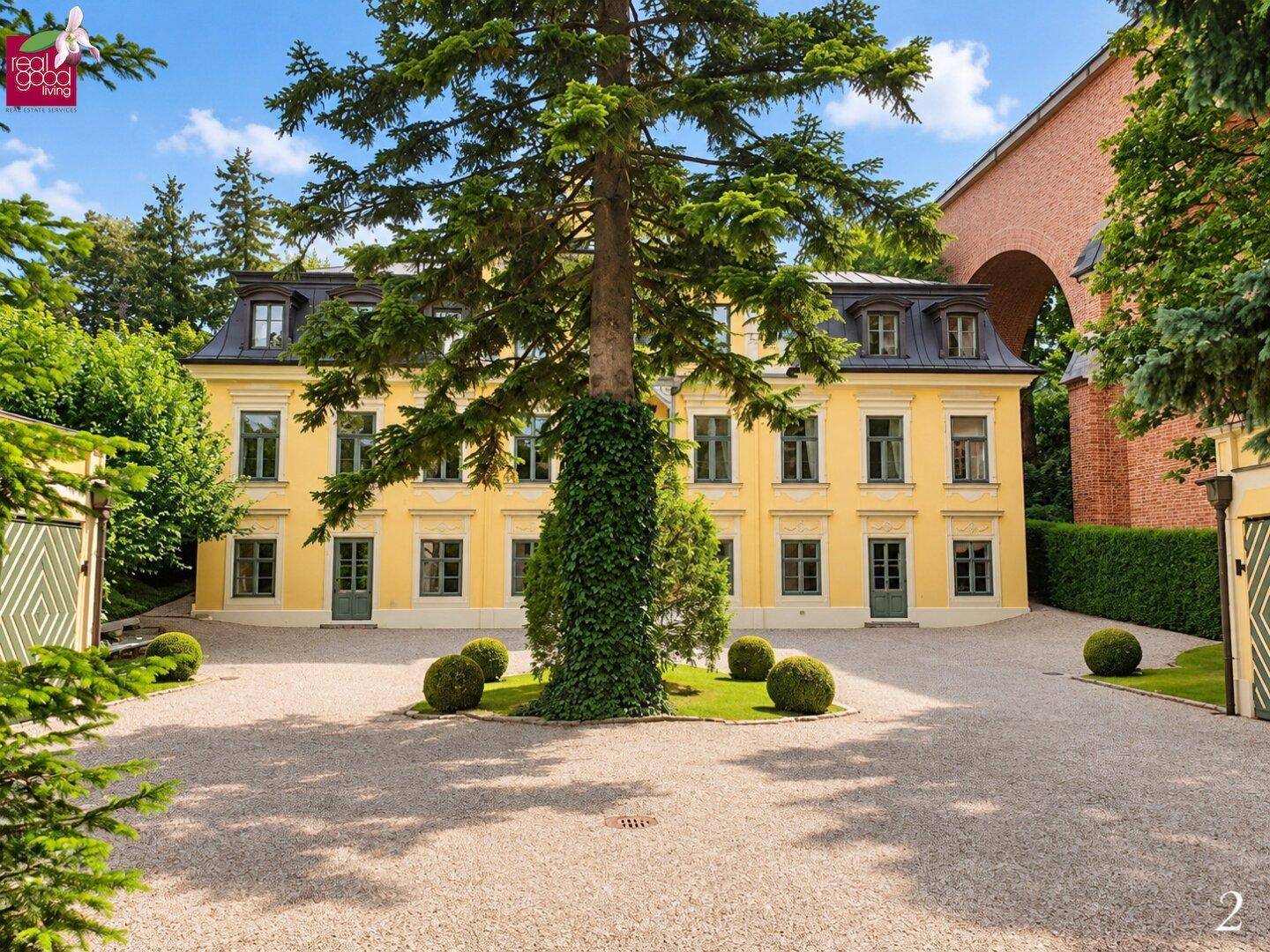 Herrschaftliche gelbe Villa mit klassischer Architektur, umgeben von einem gepflegten Vorgarten und breitem Kiesweg.