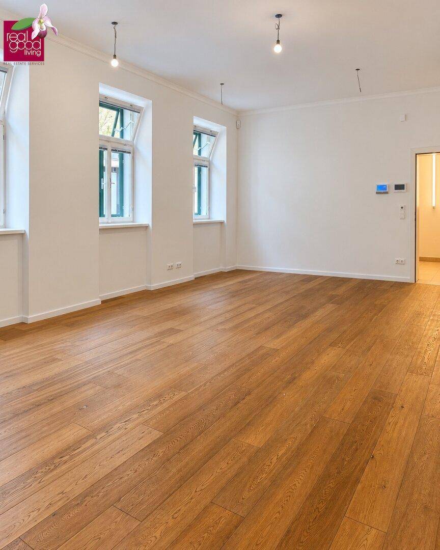 Heller, frisch renovierter Büroraum mit großen Fenstern, die viel Tageslicht hereinlassen, und elegantem Holzboden.