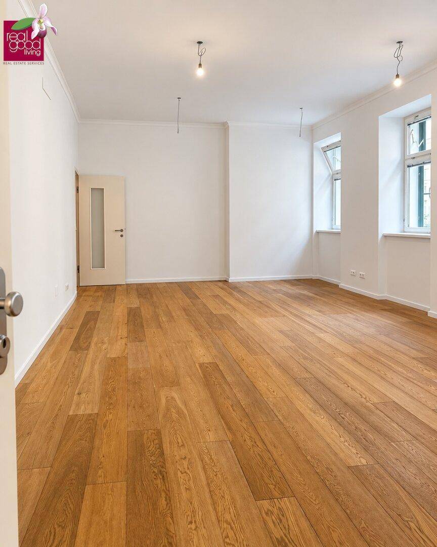 Geräumiger, heller Büroraum mit Holzboden, hohen Decken und weiß gestrichenen Wänden, bereit zur Nutzung.