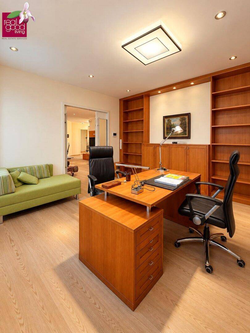 Geräumiges Arbeitszimmer mit großem Schreibtisch, Holzregalen und Blick in den angrenzenden Raum.
