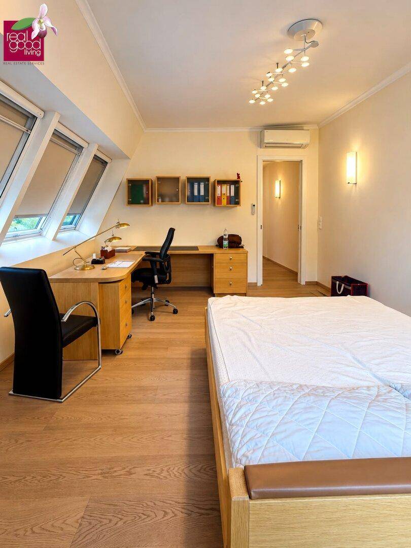 Geräumiges Schlafzimmer mit Schreibtischbereich, Dachfenstern und hellem Holzboden.