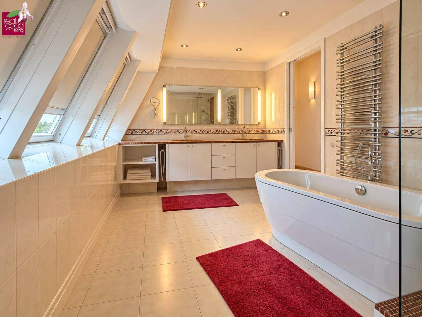 Modernes Badezimmer mit freistehender Badewanne, Doppelwaschbecken und Dachfenstern.