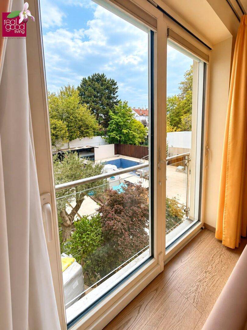 Große Fensterfront mit Blick auf den Garten und einen Swimmingpool im Freien.