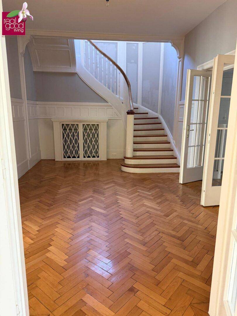 Repräsentativer Flur mit Fischgrätparkett und einer eleganten Holztreppe.