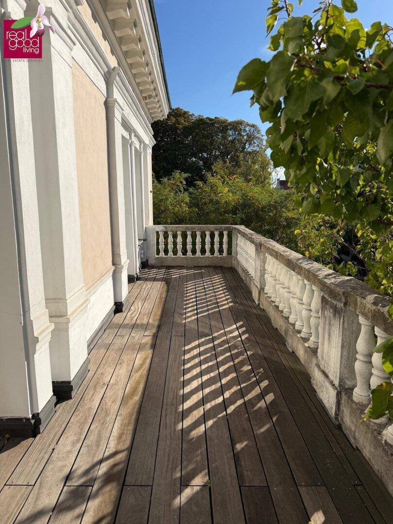 Geräumiger Balkon mit Holzboden und historischer Balustrade, ideal für sonnige Stunden.