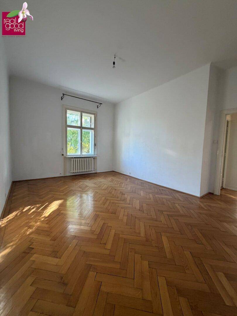 Helles Schlafzimmer mit Fischgrätparkett und einem großen Fenster, bereit zur individuellen Gestaltung.