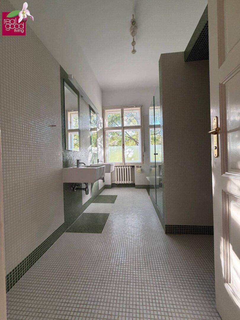 Helles Badezimmer mit Mosaikfliesen, modernem Waschbecken und begehbarer Dusche.