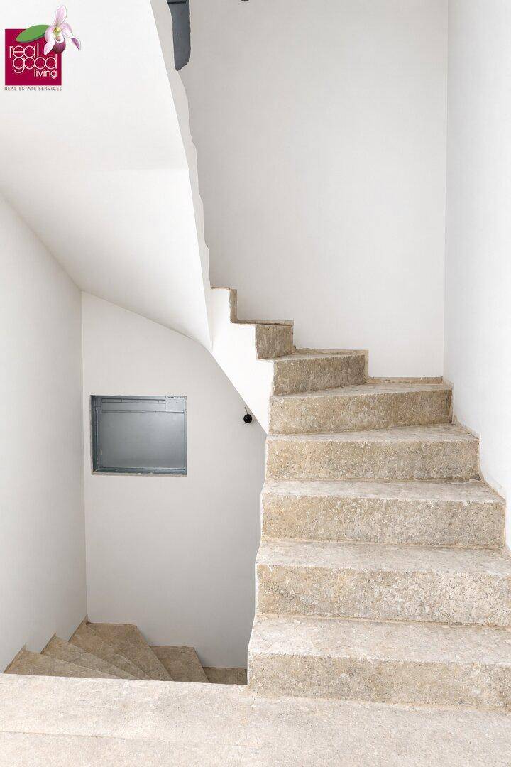 Unfertige Steintreppe in einem hellen Treppenhaus mit weißen Wänden.