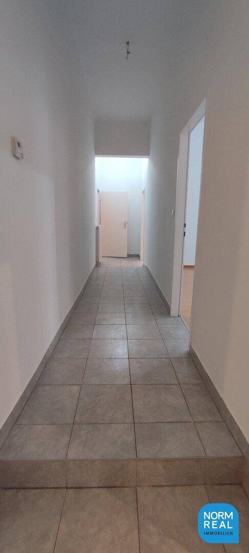 Geräumiger Flur mit Fliesenboden und Zugang zu weiteren Zimmern, bietet eine klare Raumaufteilung.