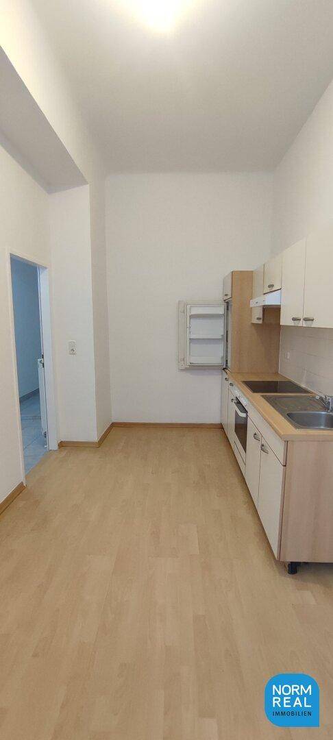 Geräumige Küche mit hoher Decke und funktionaler Einbauküche, bietet viel Potenzial.