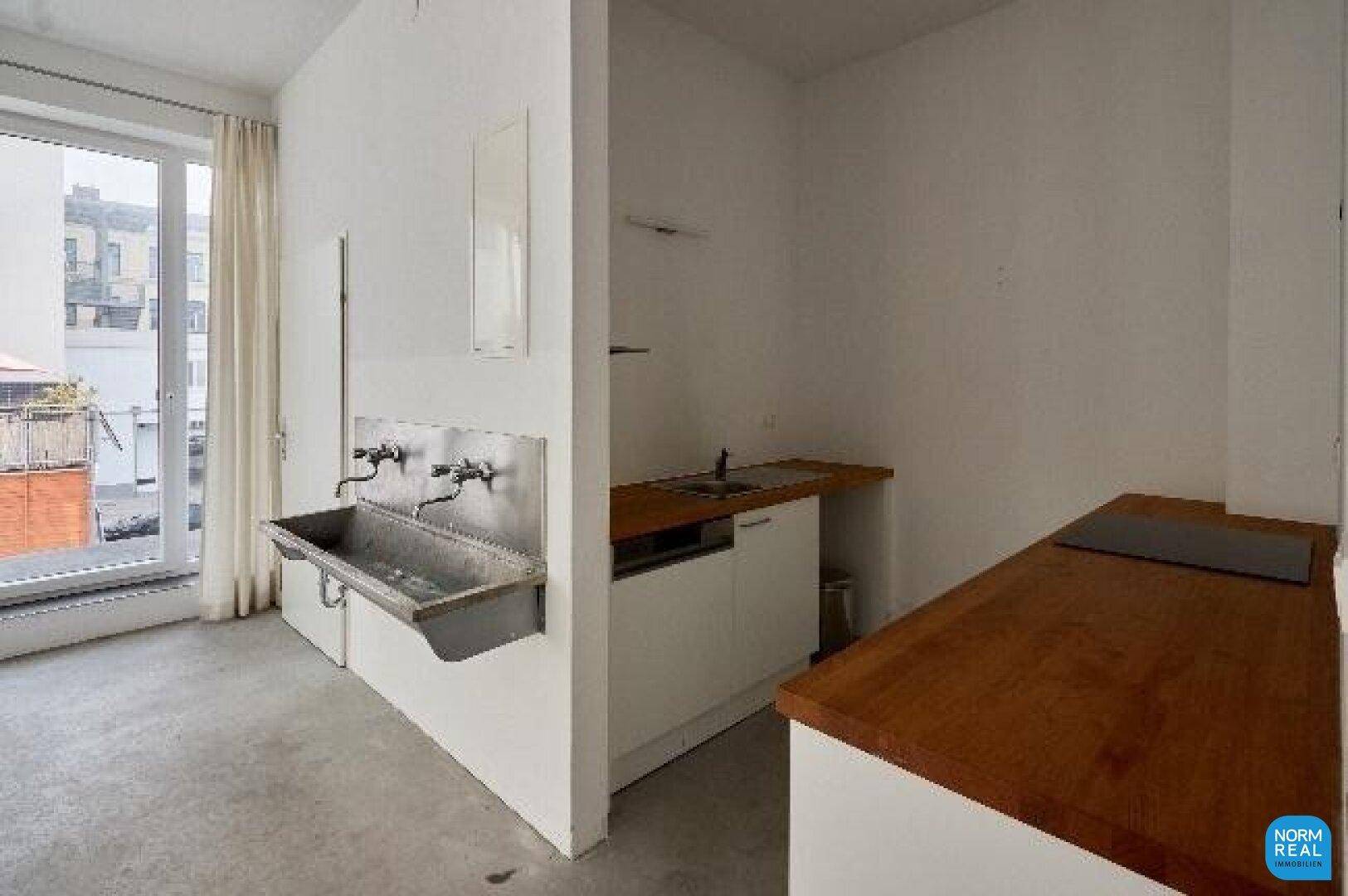Kleine Küchenzeile mit Holztheke, Spülbecken und Zugang zu einem Balkon oder einer Terrasse.