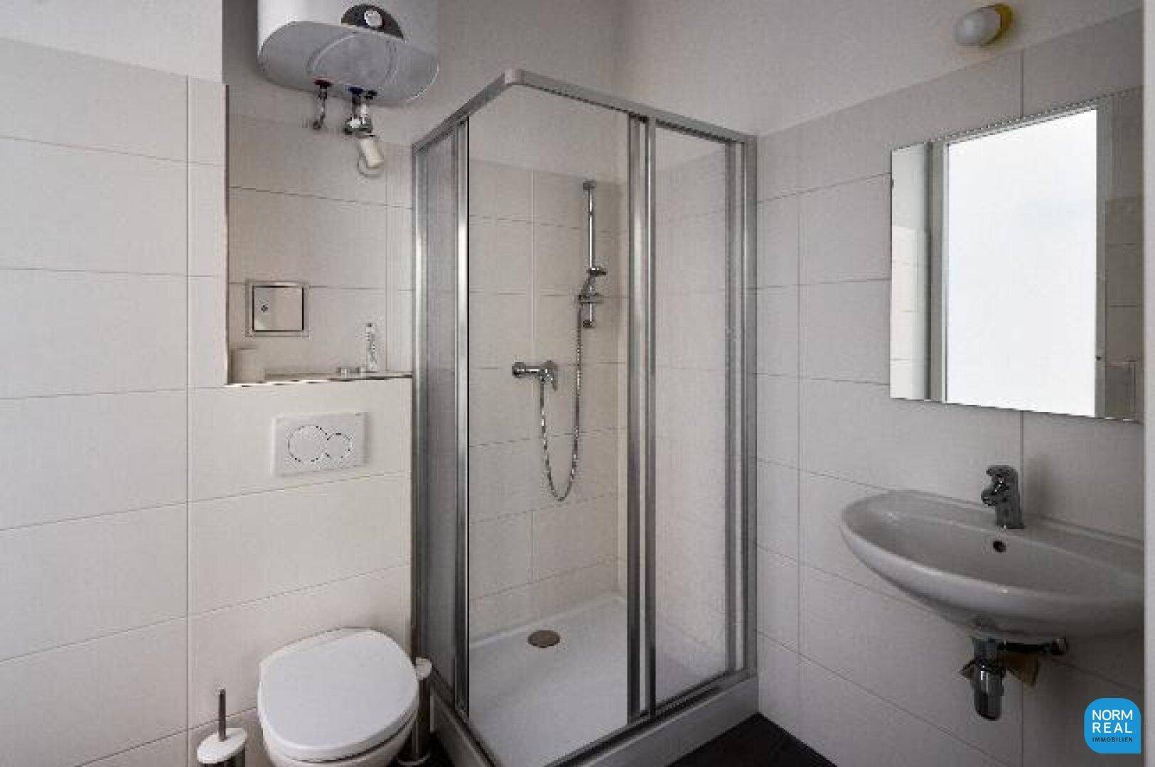 Helles Badezimmer mit Duschkabine, WC, Waschbecken und weiß gefliesten Wänden.