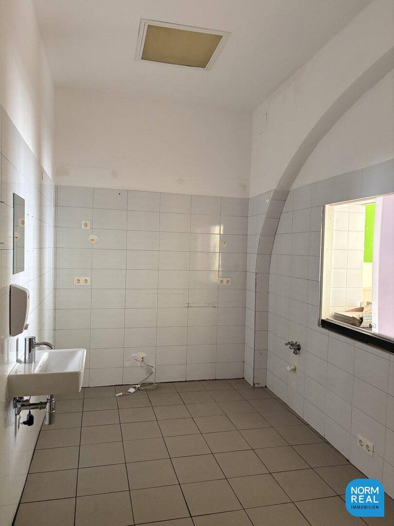 Gefliester Raum mit Waschbecken und einem Fenster, möglicherweise ein Hauswirtschaftsraum.