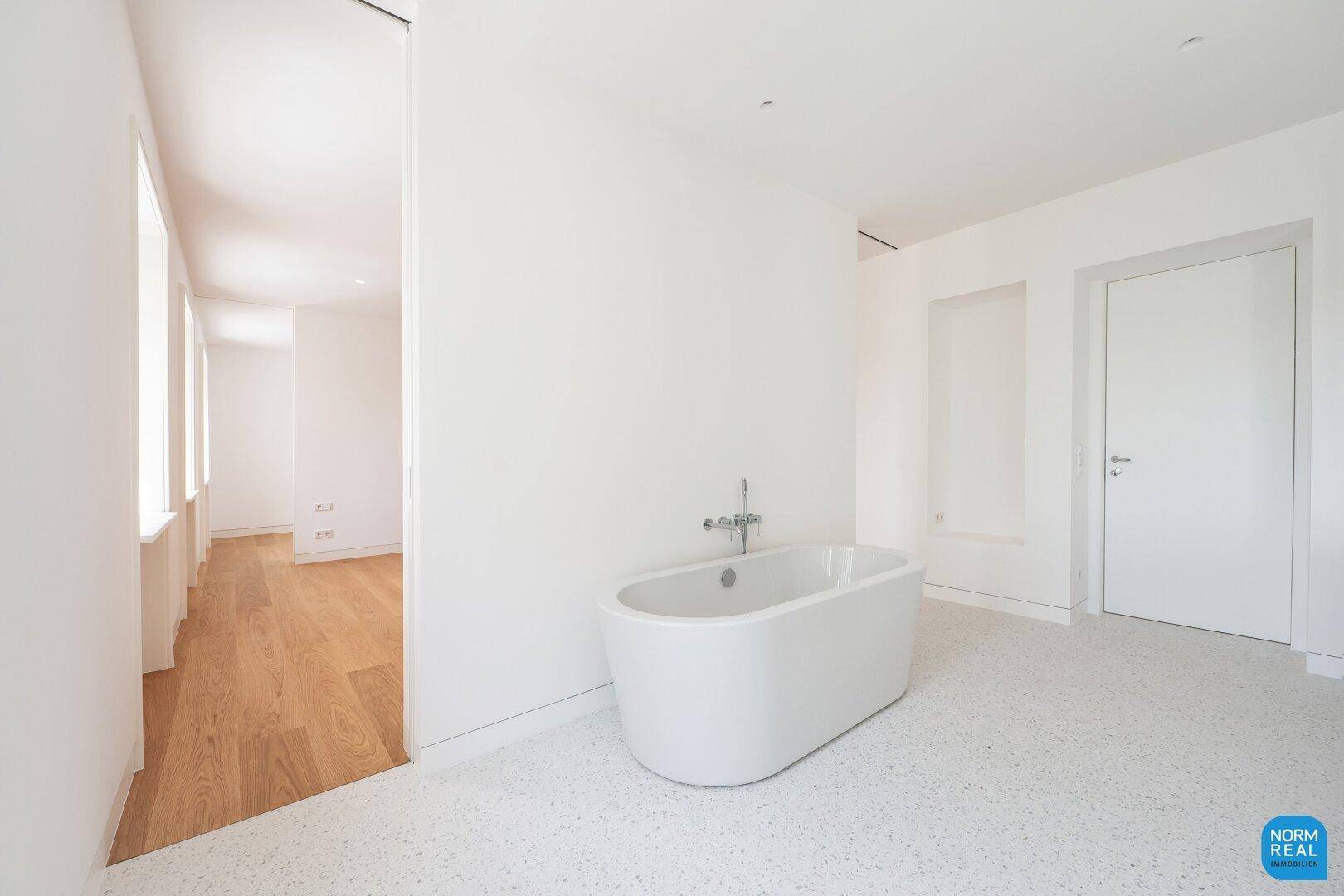 Modernes Badezimmer mit einer freistehenden Badewanne und hellem Terrazzoboden.