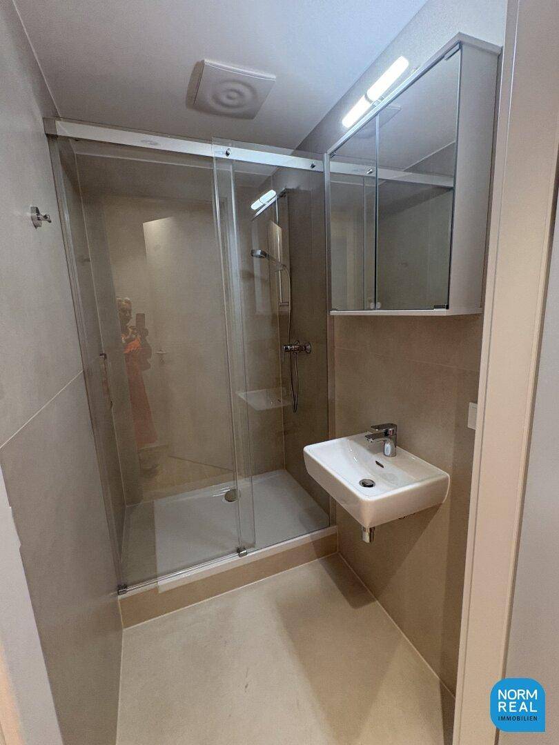 Kompaktes Badezimmer mit Duschkabine, Einzelwaschbecken und Spiegelschrank.