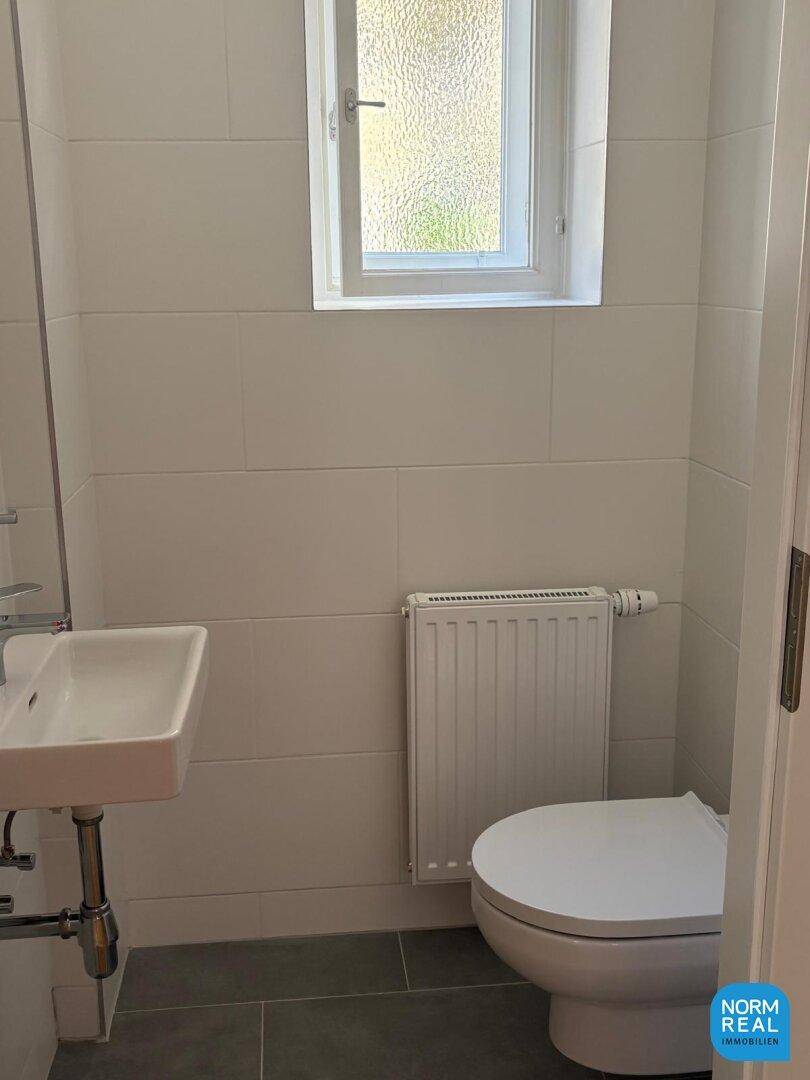 Kleines Gäste-WC mit Toilette, Waschbecken und Fenster für natürliche Belüftung, sehr praktisch und hell.