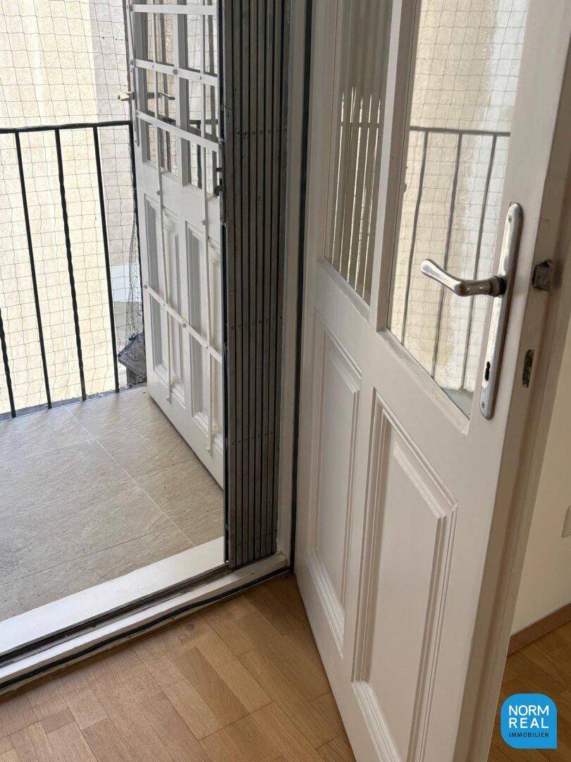 Zugang zu einem kleinen Balkon mit Fliesenboden und Metallgeländer, ideal für frische Luft und Entspannung.