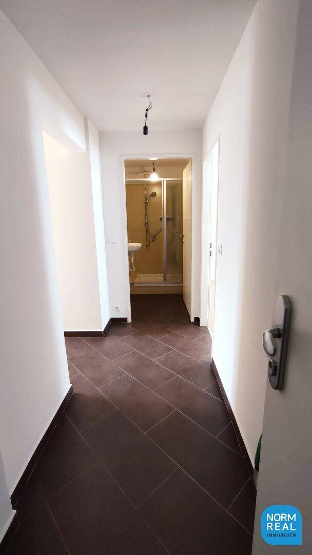 Heller Flur mit Fliesenboden, der zu weiteren Räumen und einem Badezimmer führt.
