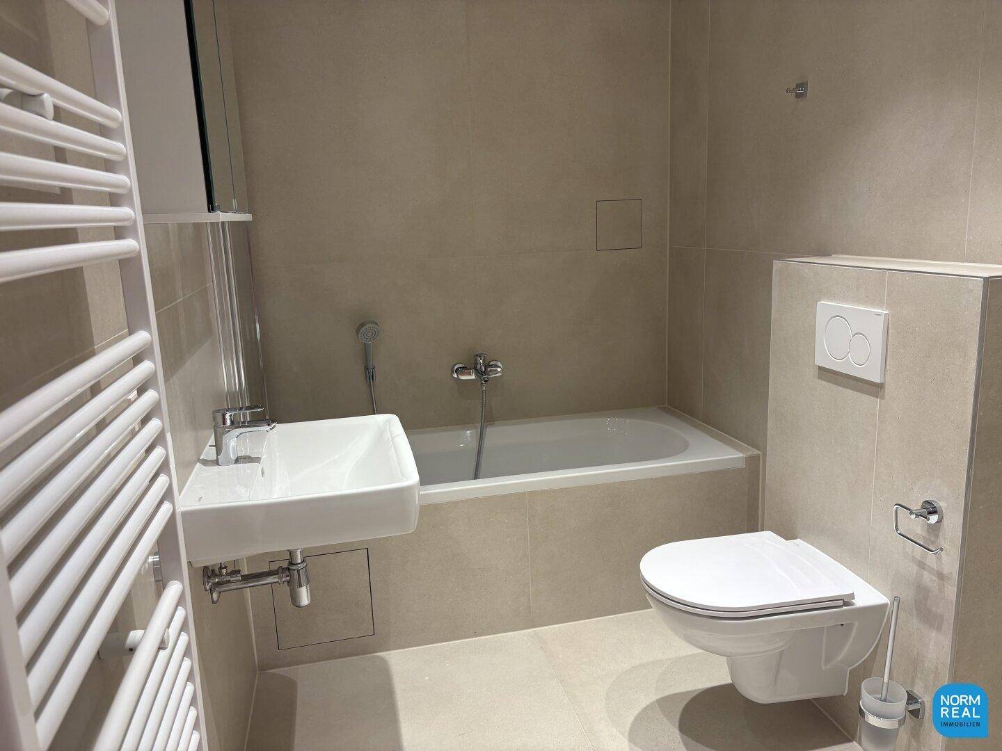 Helles Badezimmer mit Badewanne, wandhängendem WC und beheiztem Handtuchhalter.