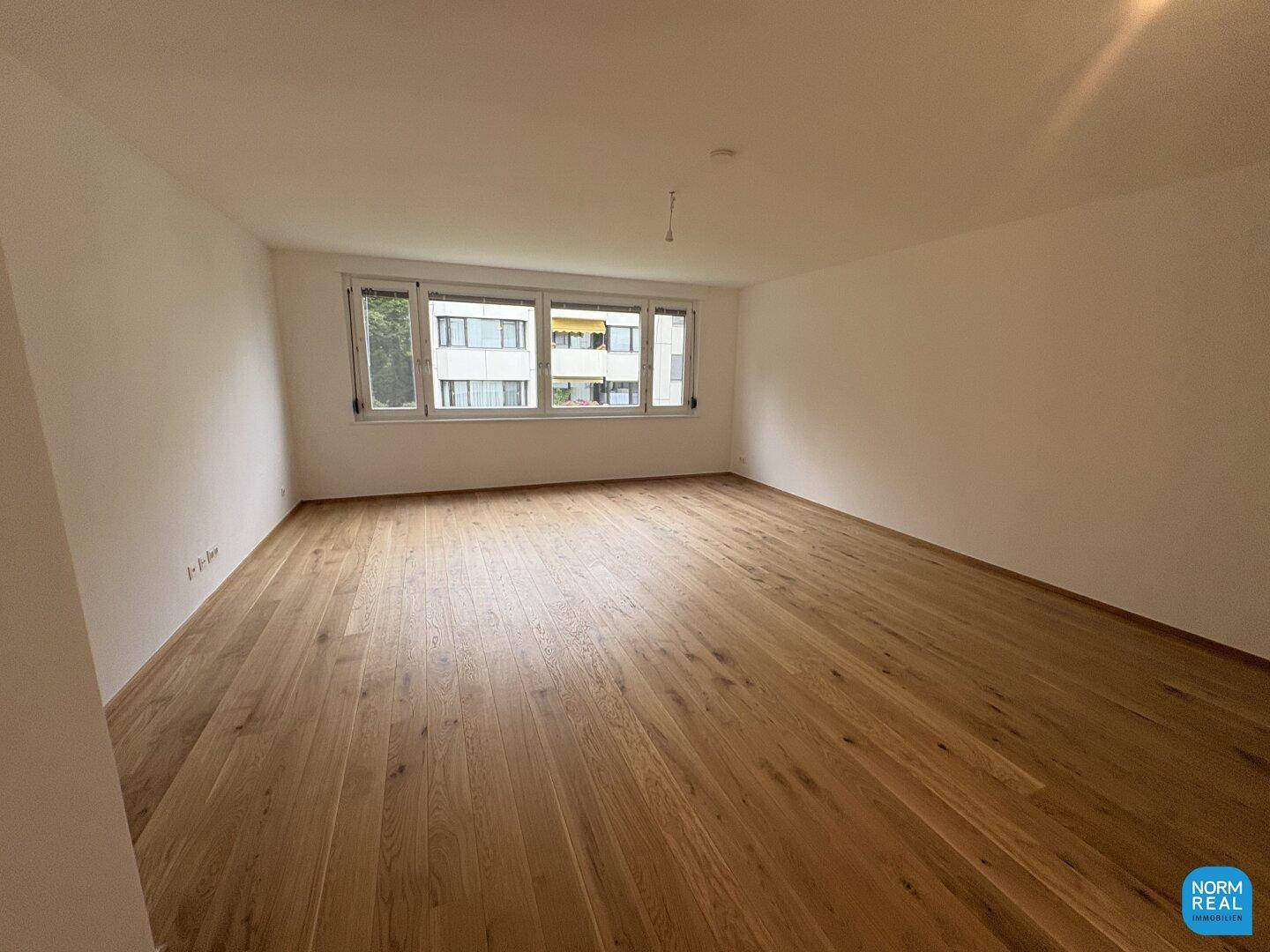 Geräumiges Schlafzimmer mit Holzboden und großen Fenstern, die viel Tageslicht hereinlassen.